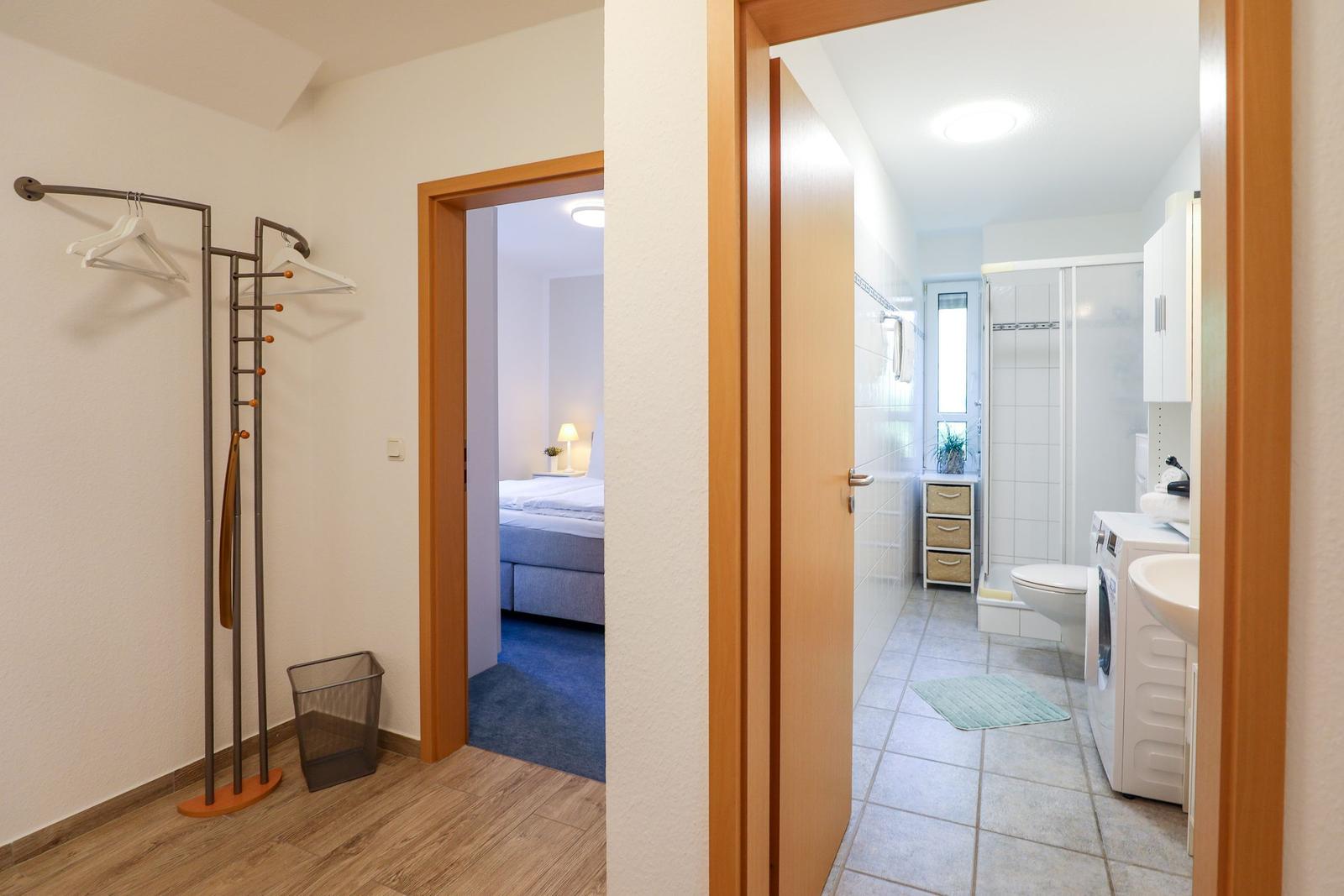 Flur mit Garderobe, Schlafzimmer und Badezimmer mit Dusche und Waschmaschine.