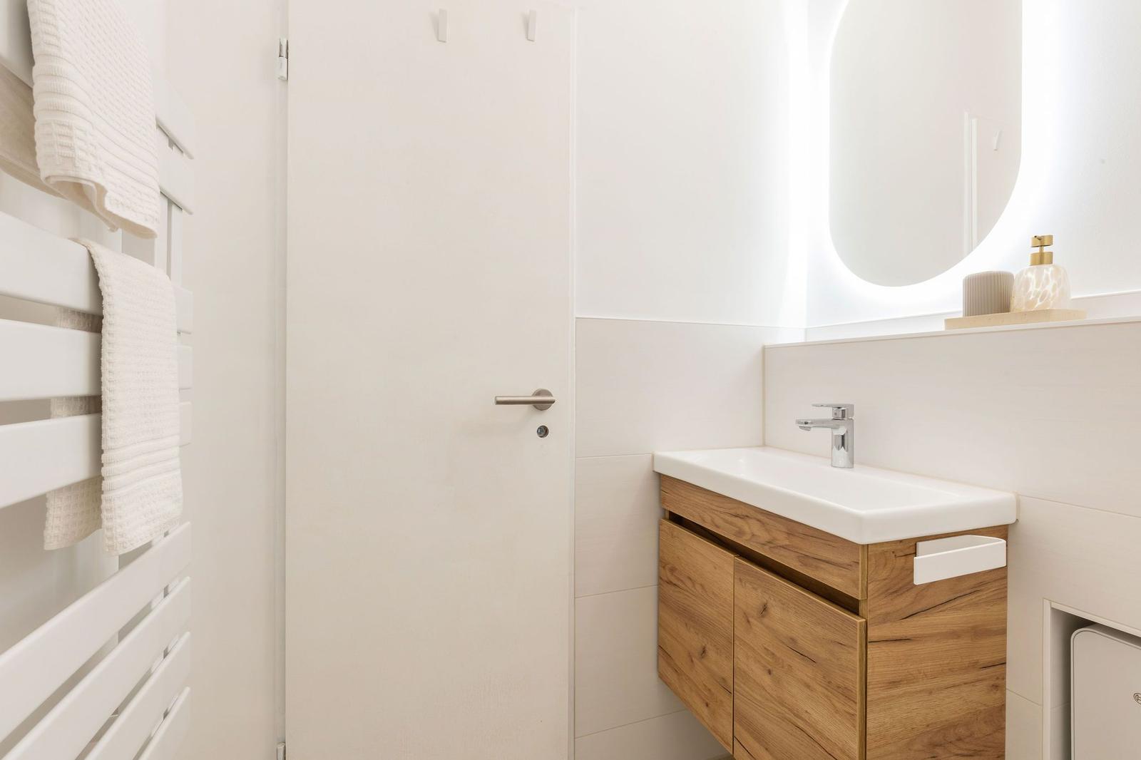Badezimmer mit Waschbecken, Spiegel und Handtuchhalter.