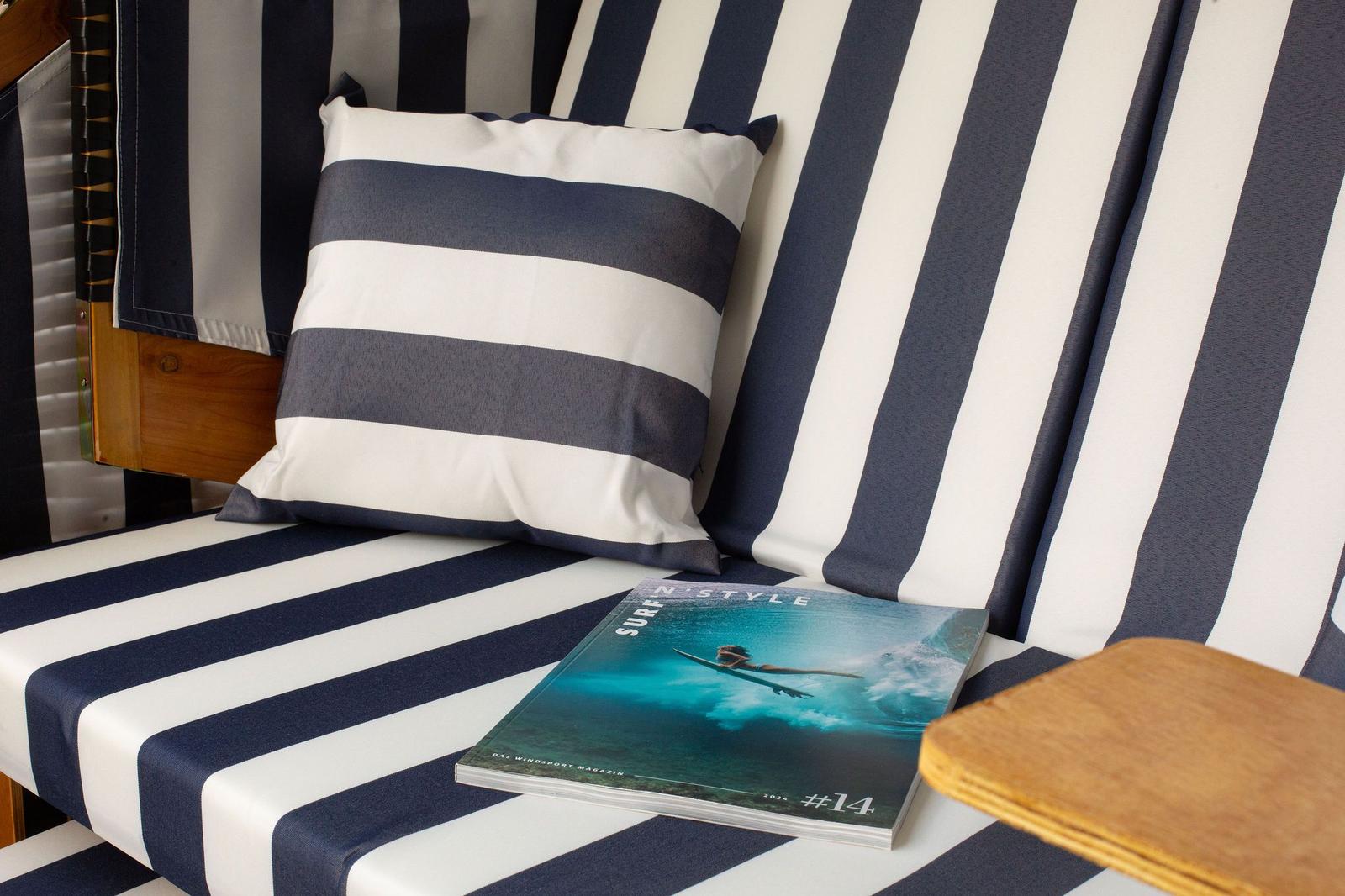 Strandliege mit Streifenkissen und Surf-Magazin.