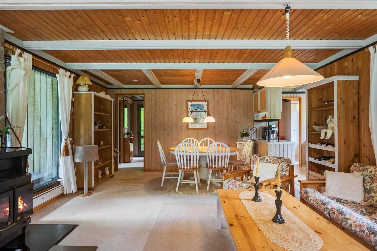 Wohn- und Essbereich mit Holzdecke, Esstisch, Sofa und Kamin.