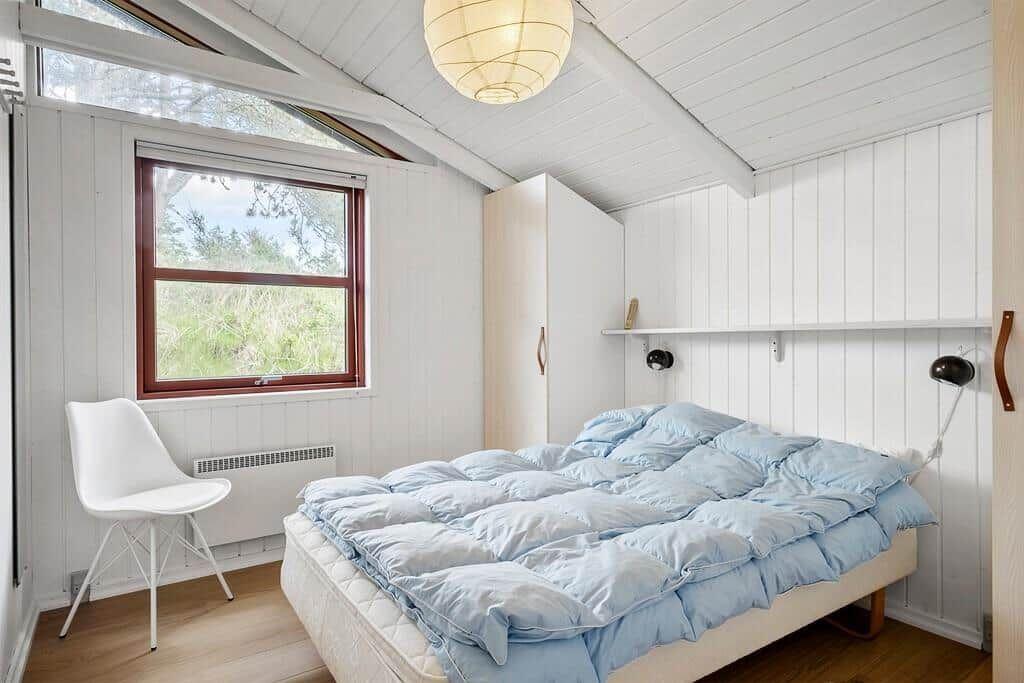 Schlafzimmer mit Bett, Fenster und Lampe