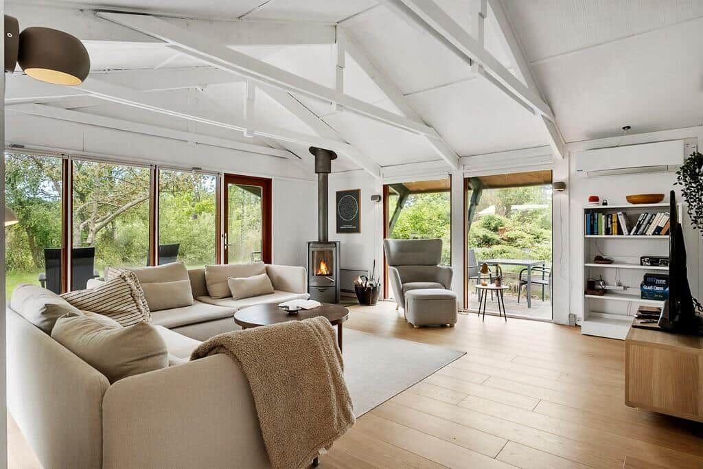 Wohnzimmer mit Sitzgruppe, Kamin und großflächigen Fenstern zur Außenterrasse.