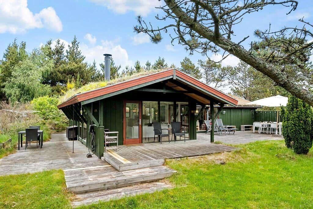 Moderne Holzhütte mit Grasdach, Terrasse und Garten. Außenbereich mit Sitzgelegenheiten.