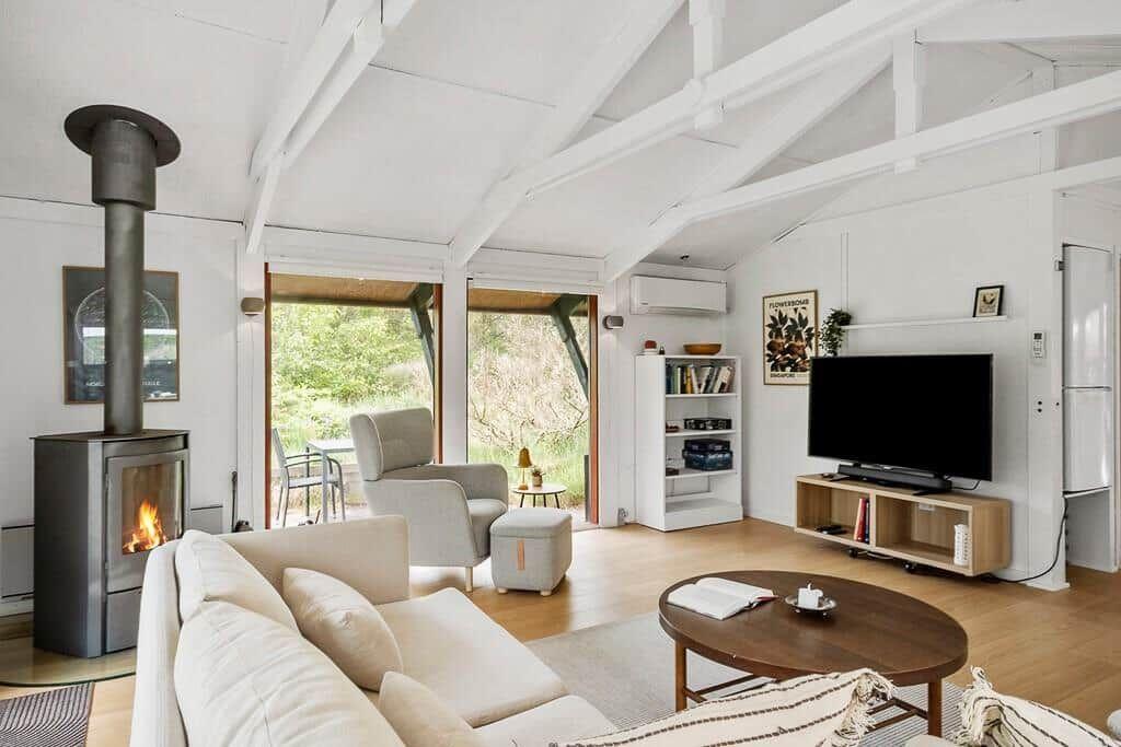 Wohnzimmer mit Kamin, Sofa, Fernseher und Blick auf Garten