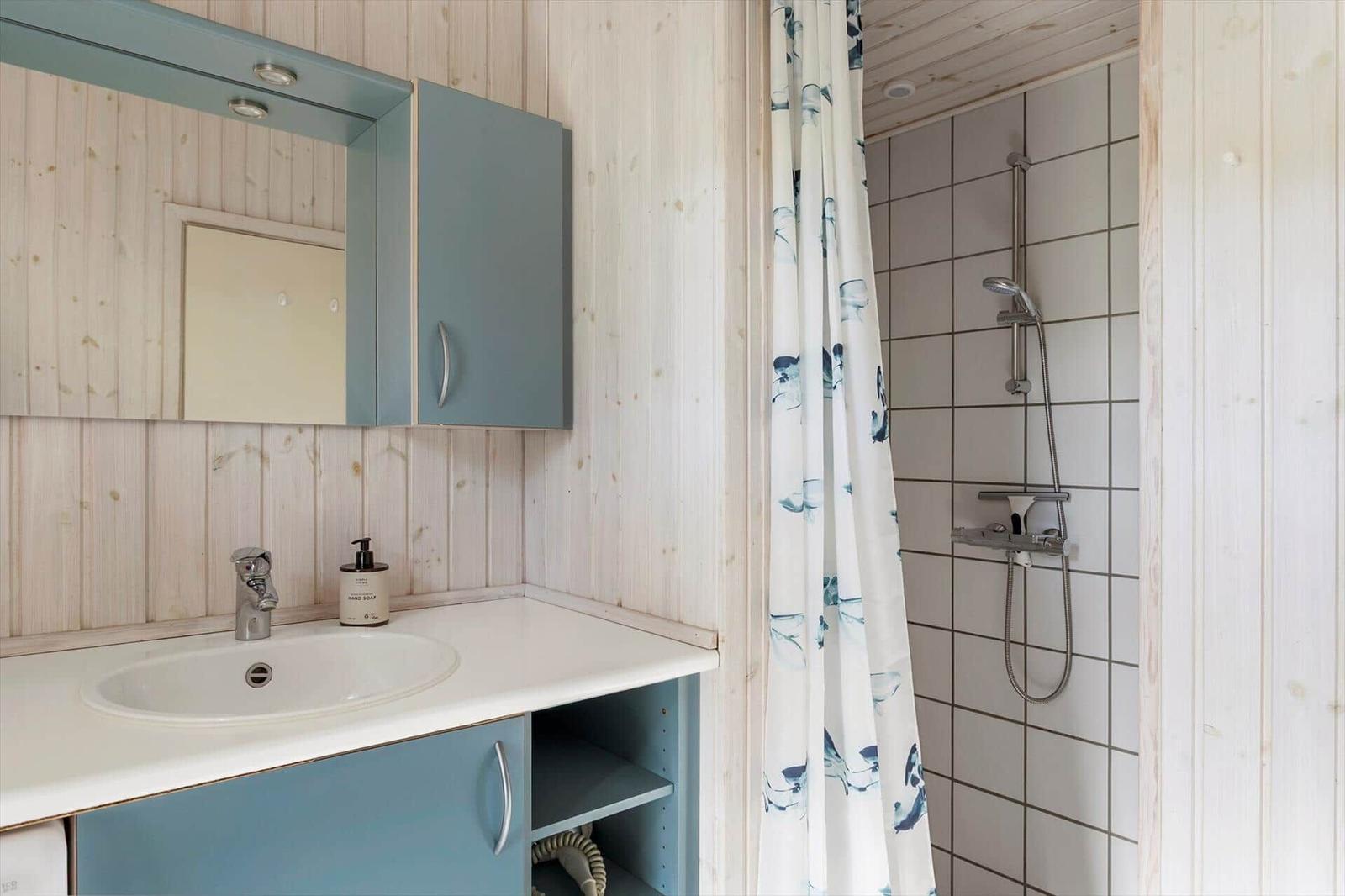 Bad mit Waschbecken, Spiegelschrank und Dusche mit Duschvorhang.