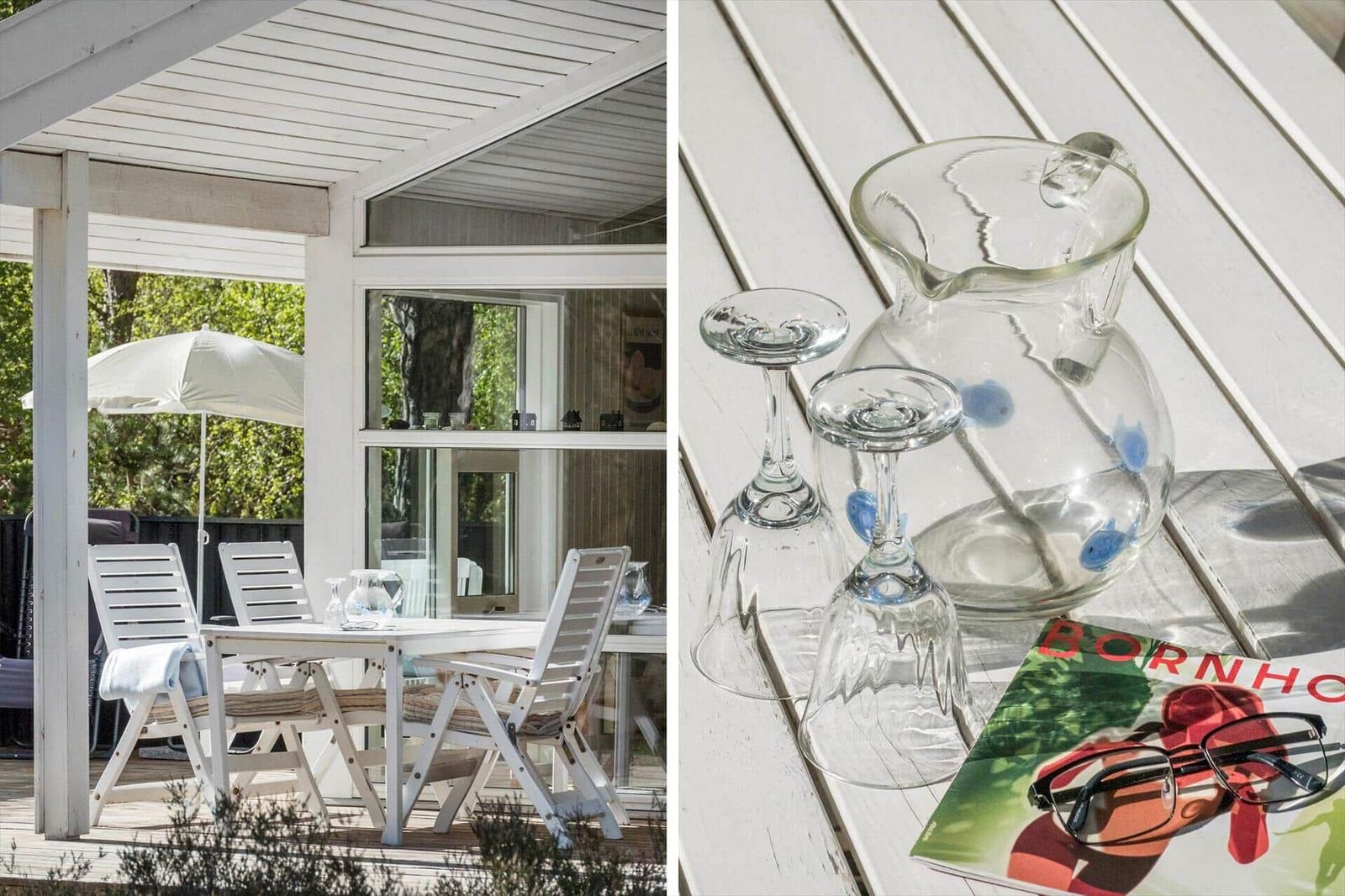 Terrasse mit weißem Tisch und Stühlen, Glasgäste und Karaffe auf Tisch.