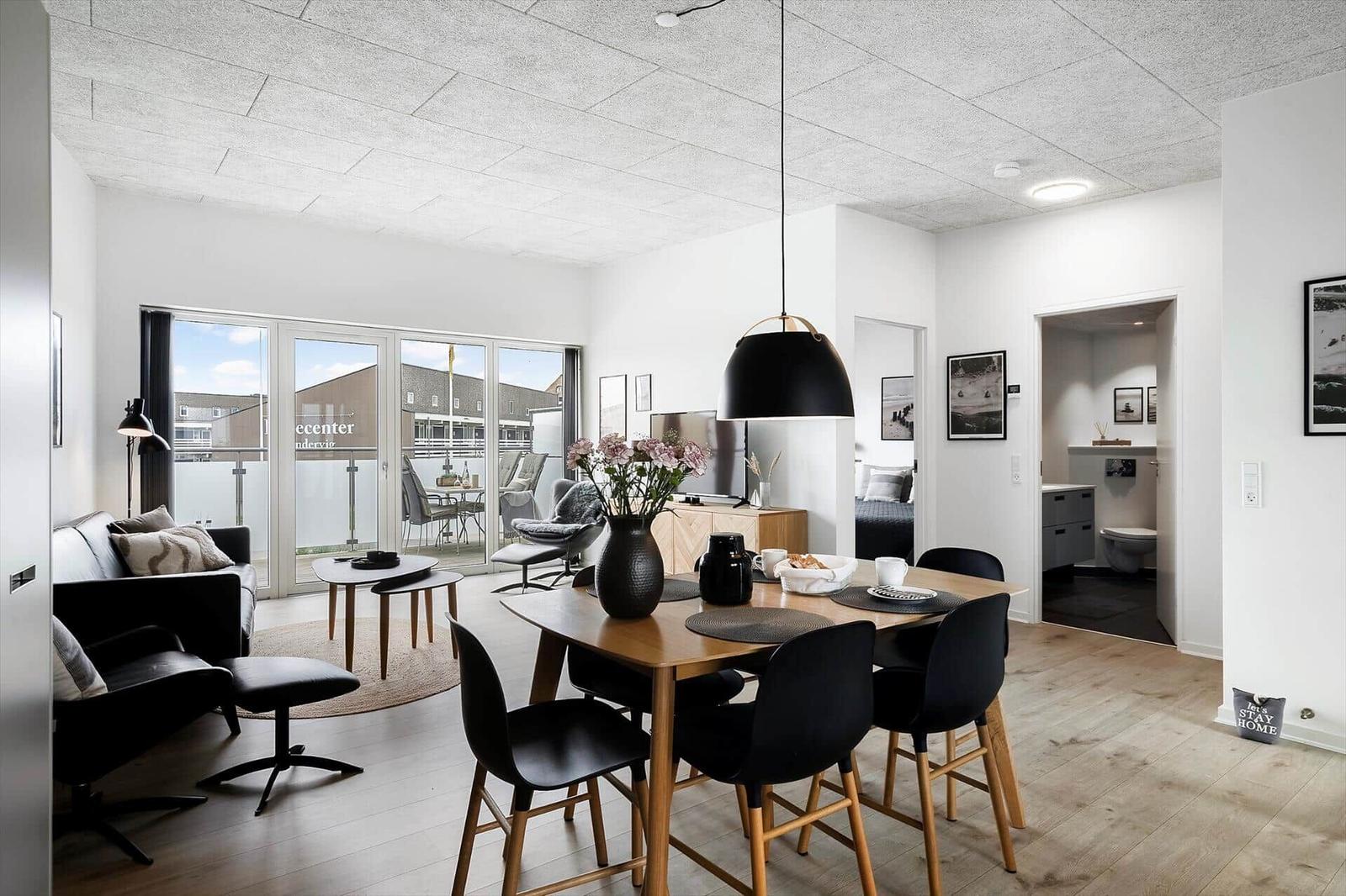 Wohn- und Essbereich mit Balkon, Esstisch und moderner Beleuchtung.