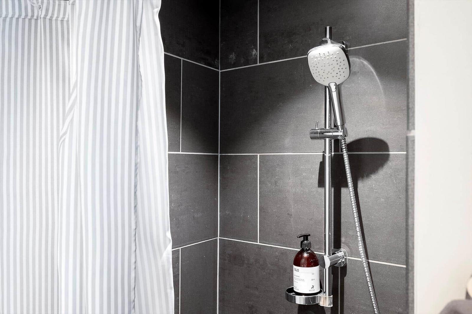 Dusche mit Handbrause und Duschvorhang aus Streifenstoff.