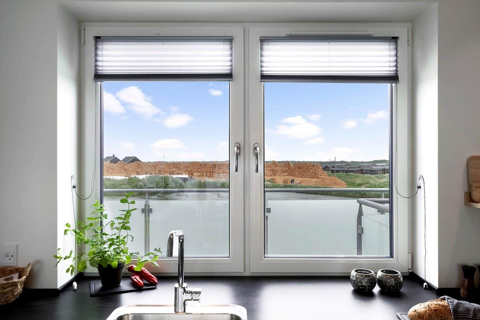 Küche mit Blick auf Wasser und Landschaft durch große Fenster.