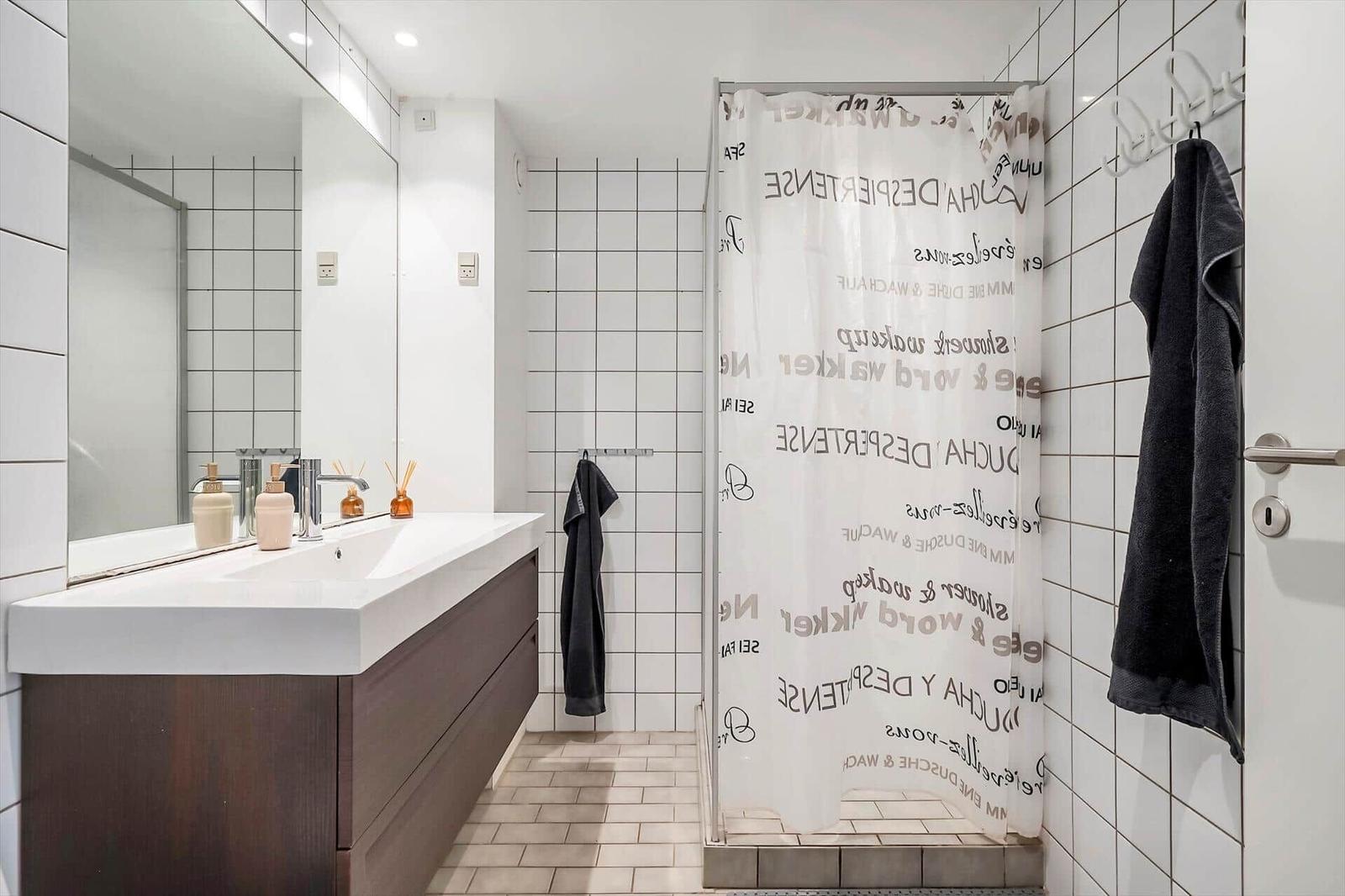 Badezimmer mit Dusche, Waschbecken und Spiegel