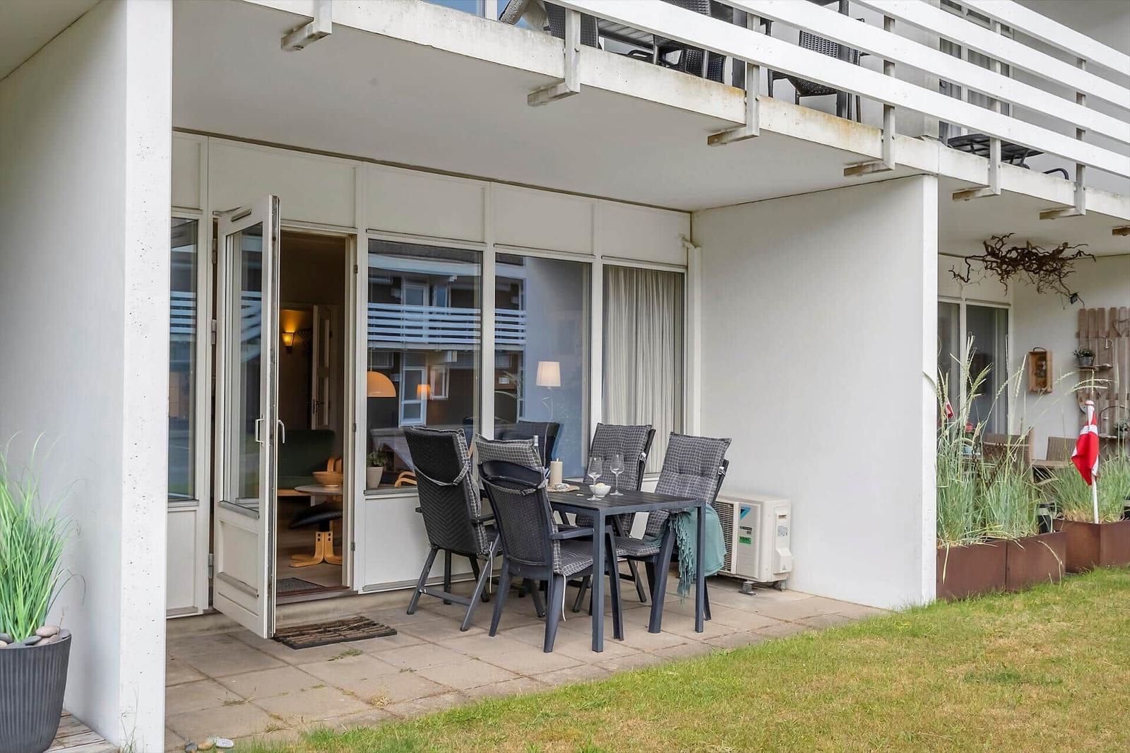 Terrasse mit Sitzgruppe und Blick ins Haus. Gartenbereich mit Pflanzen und Flagge.