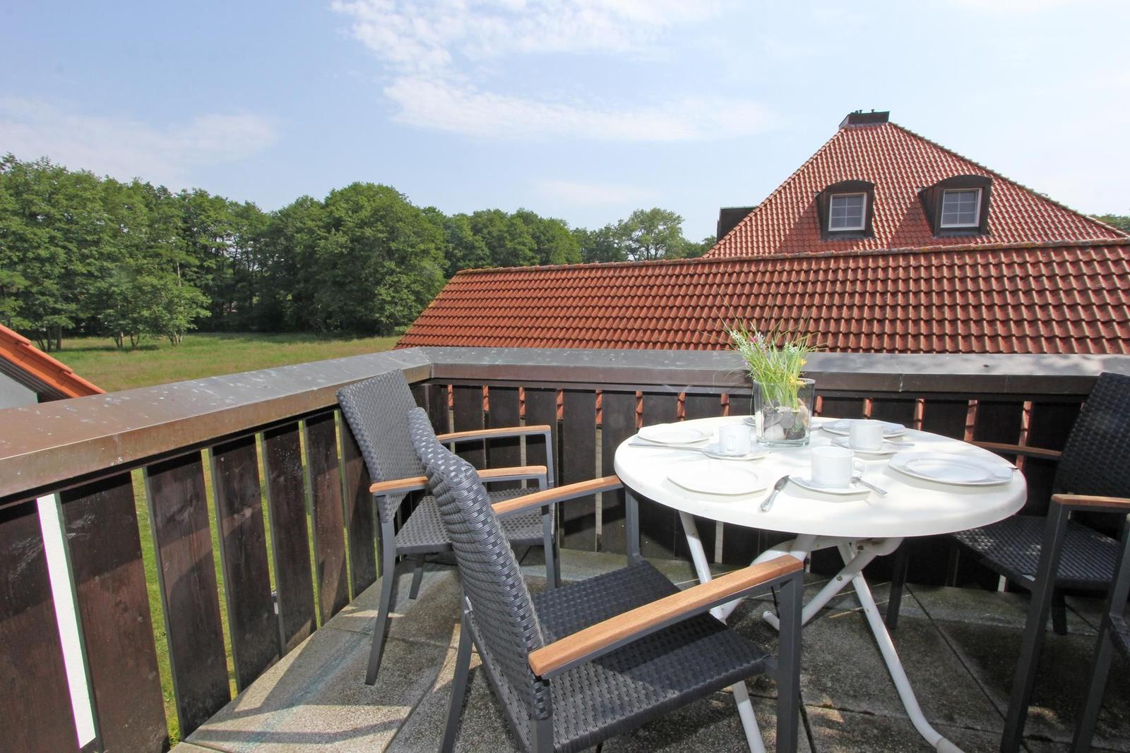 Terrasse mit Tisch und Stühlen, Blick auf Dach und Wald.