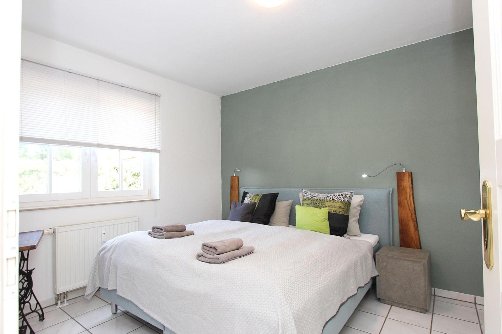 Schlafzimmer mit Bett, Fenster und grüner Wand
