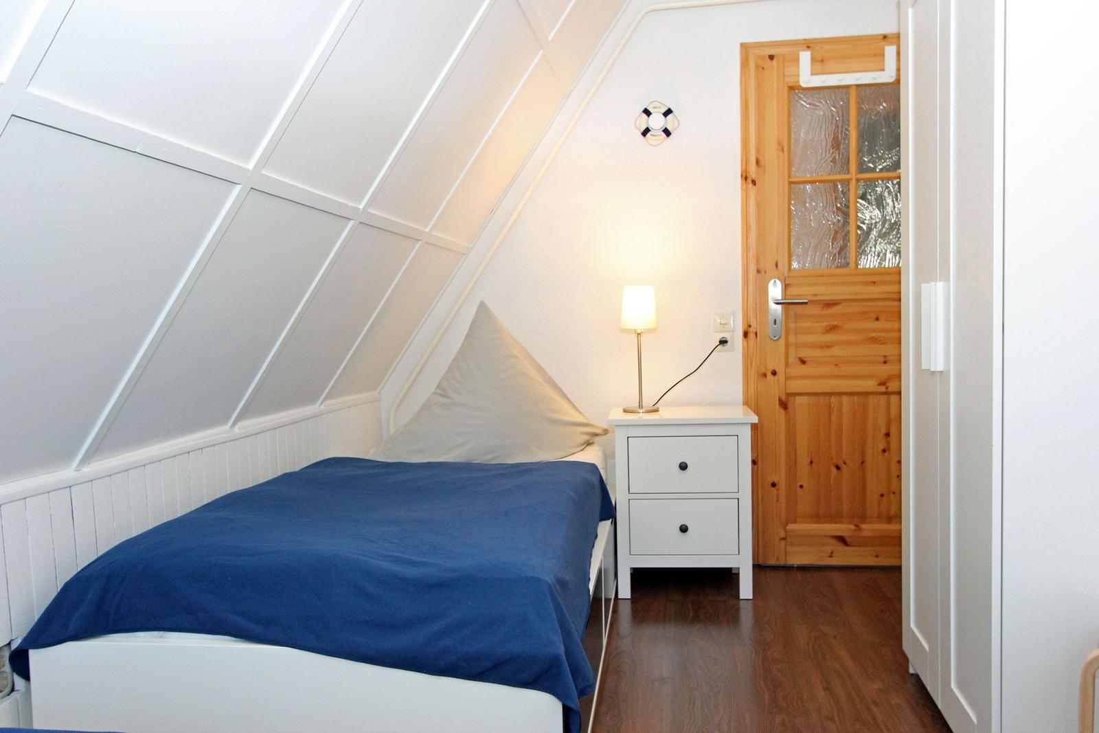 Schlafzimmer mit Bett, Nachttisch und Holztür