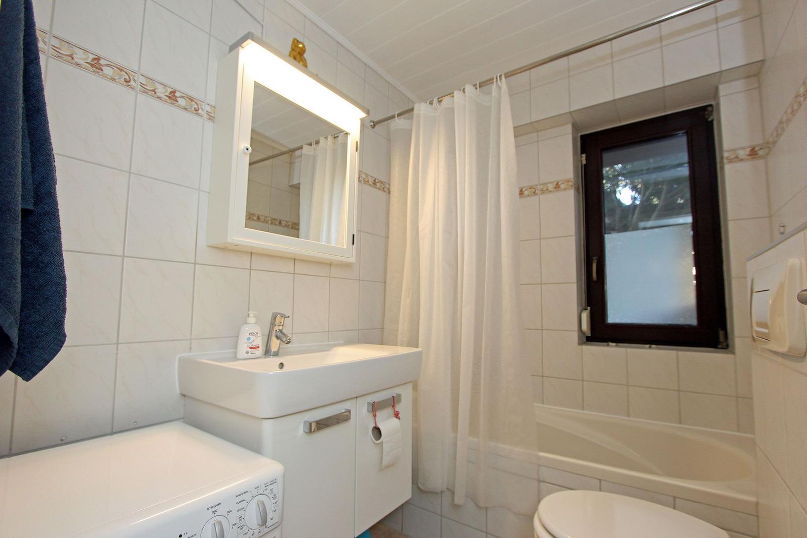 Badezimmer mit Waschbecken, Spiegel, Dusche, Badewanne und Fenster.