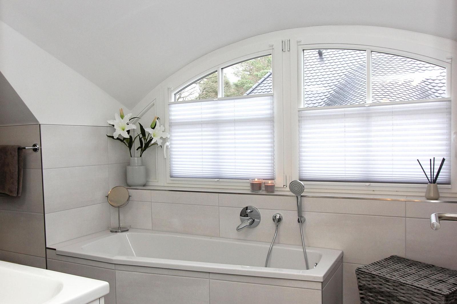 Bad mit Badewanne, Fenster mit Jalousien und Blumen
