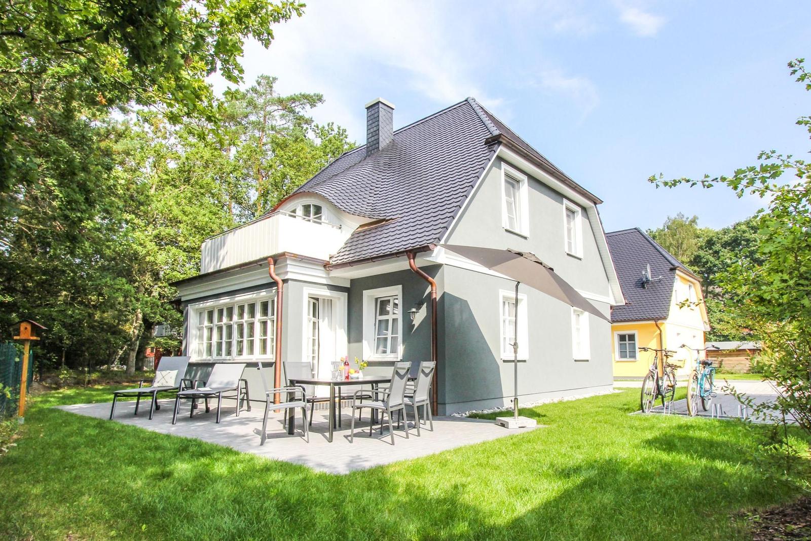 Ein zweistöckiges Haus mit Terrasse und Garten. Fahrräder stehen bereit.