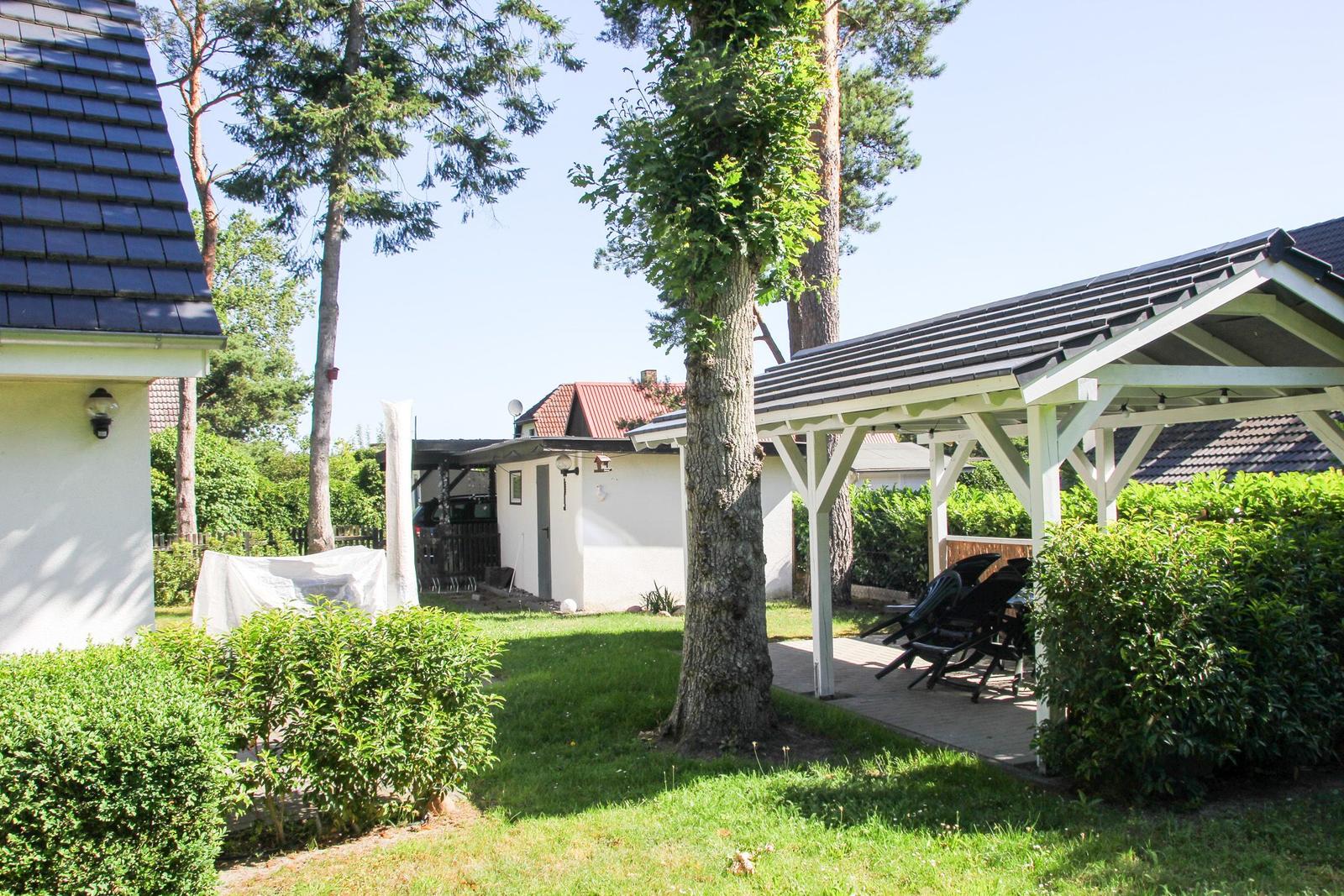 Hinterhof mit Pavillon, Gartenmöbeln, Bäumen und Rasenfläche.
