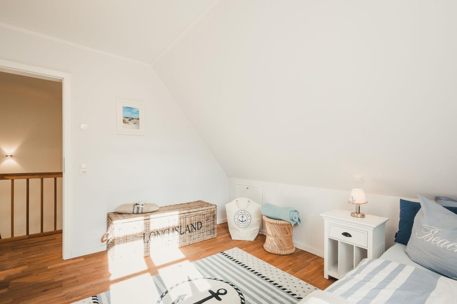 Schlafzimmer mit Dachschrägen, Bett, Nachttisch und Stauraumkiste.