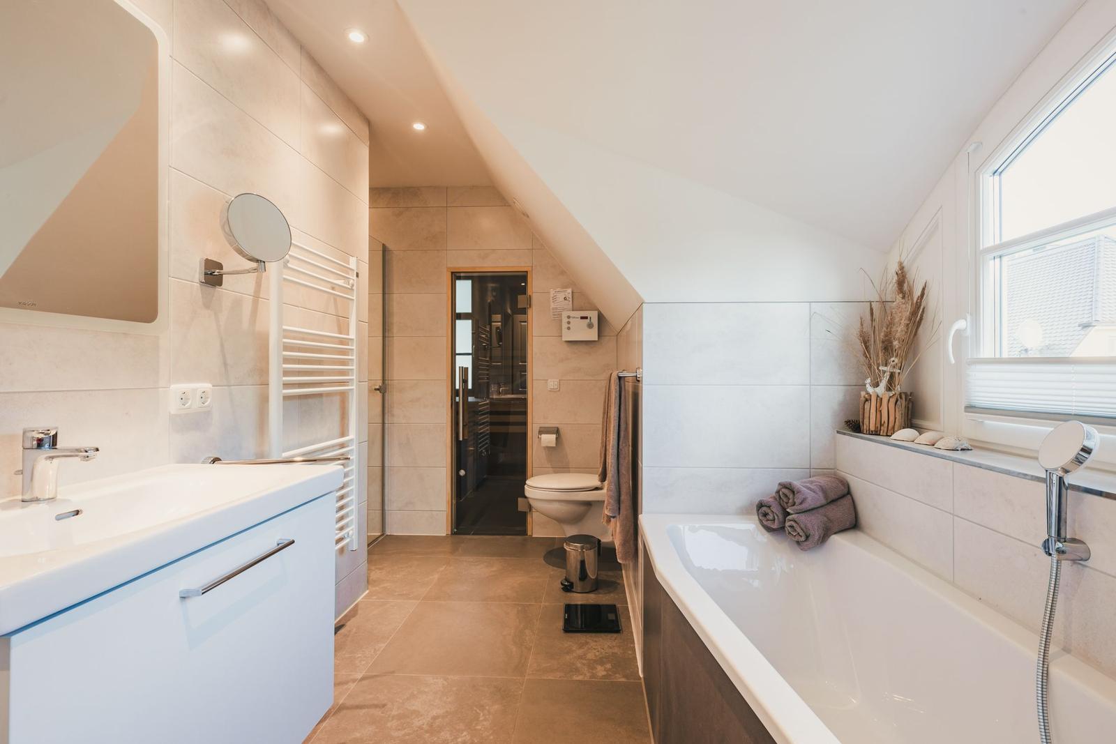Badezimmer mit Badewanne, Dusche und Toilette unter Dachschräge