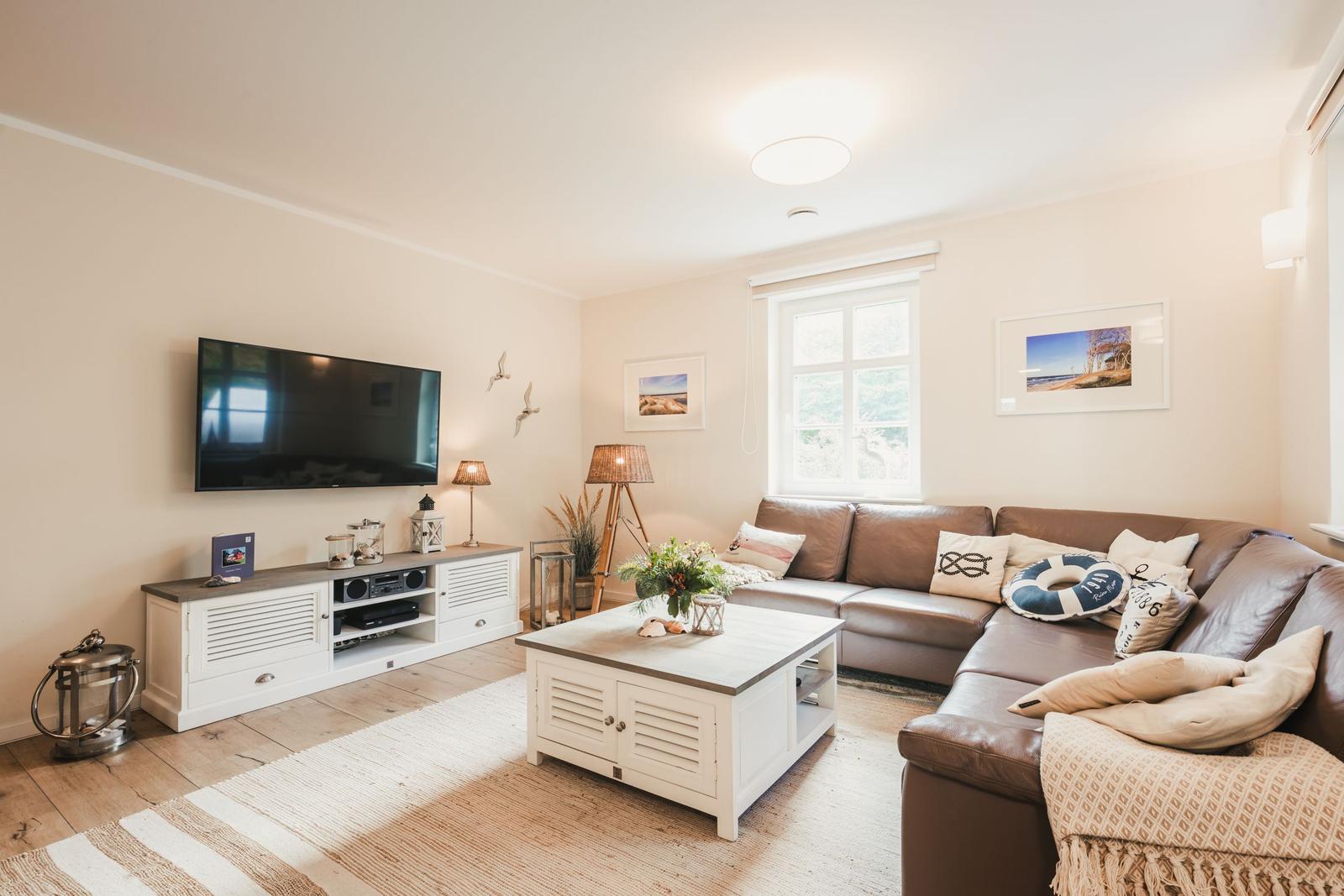 Wohnzimmer mit Sofa, Couchtisch und Fernseher an der Wand.