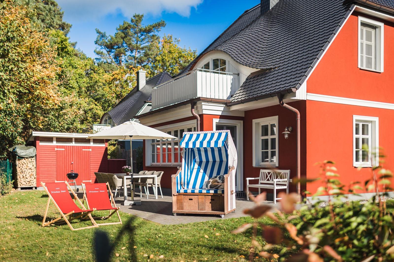 Rotes Haus mit Balkon, Gartenbereich und Strandkorb.