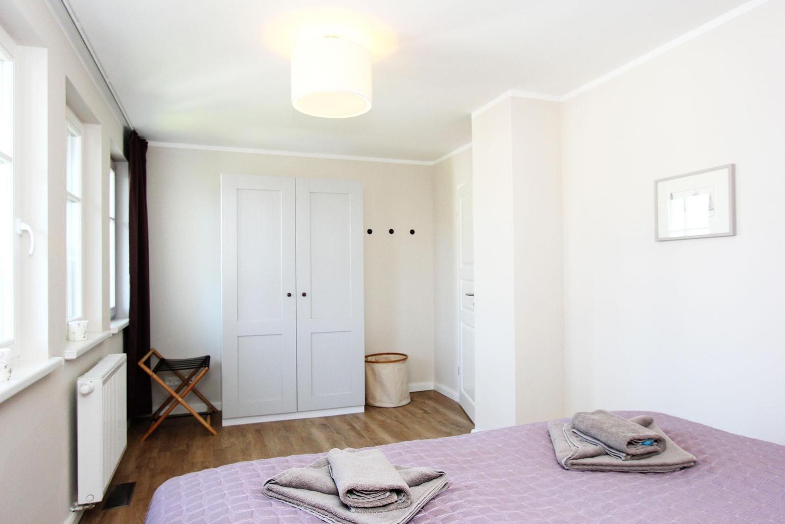 Schlafzimmer mit Bett, Kleiderkabinett und Fenster.