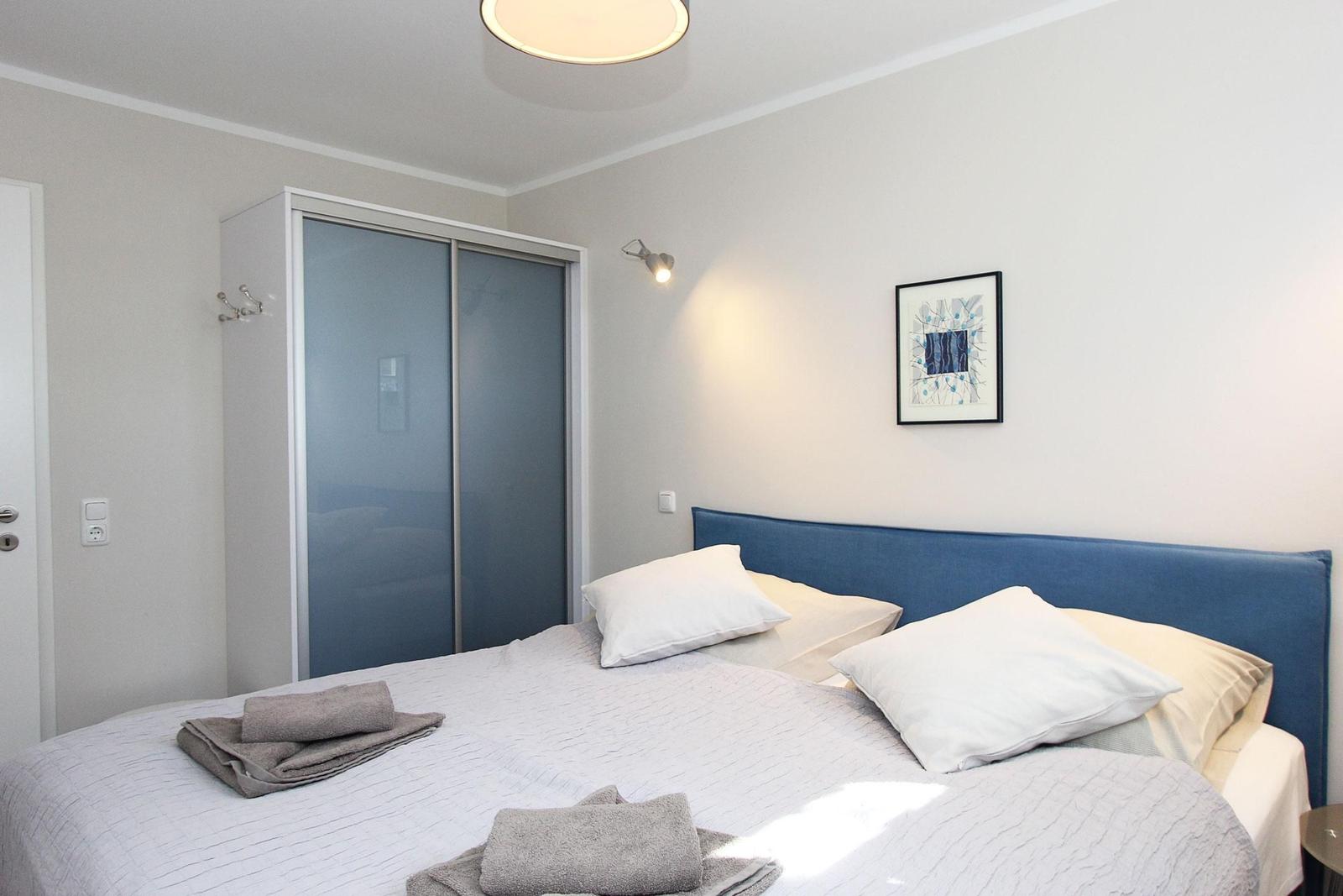 Schlafzimmer mit Bett, Kleiderschrank und Wandbild.