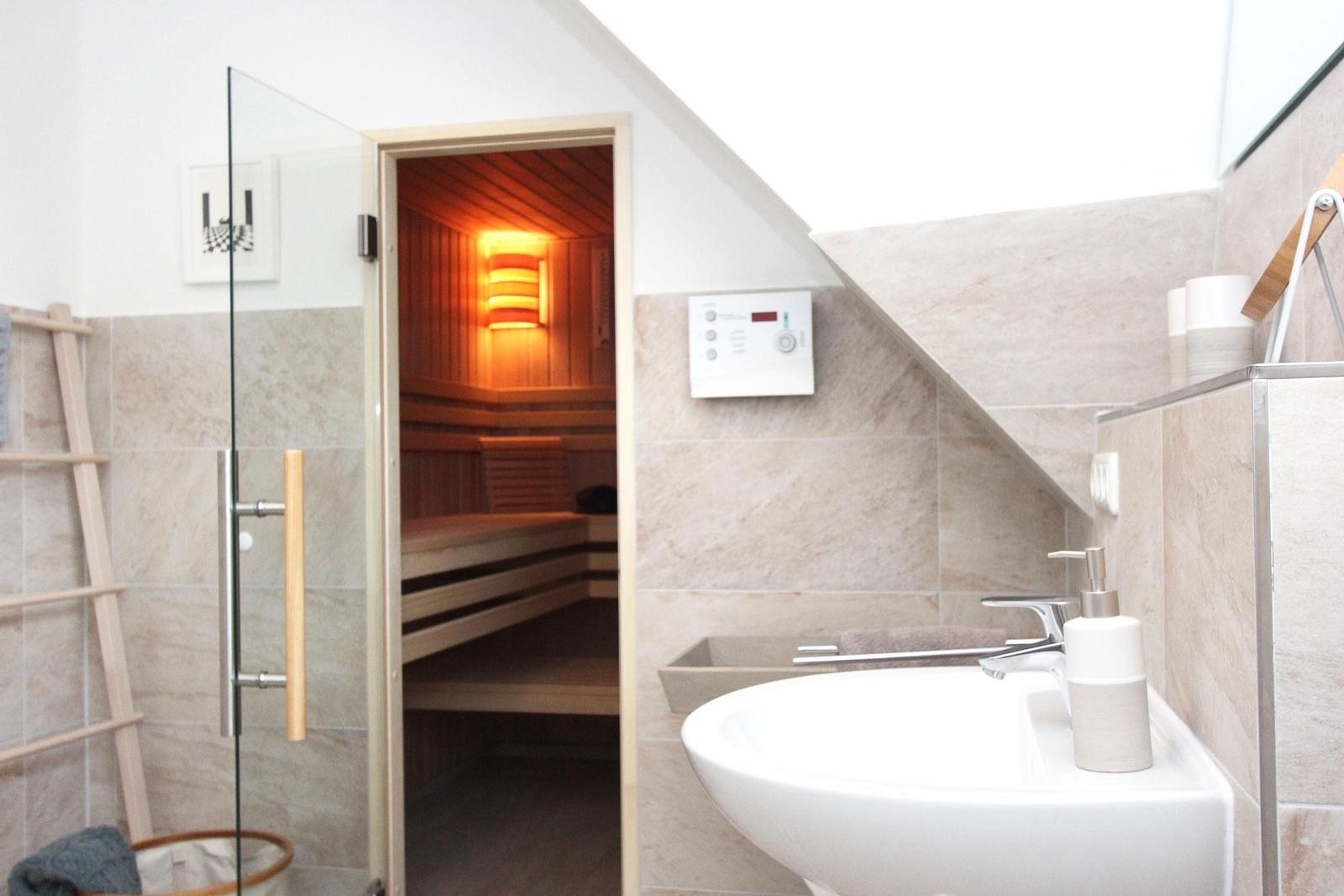 Dusche mit Sauna, Waschbecken und Steuerungseinheit an der Wand.