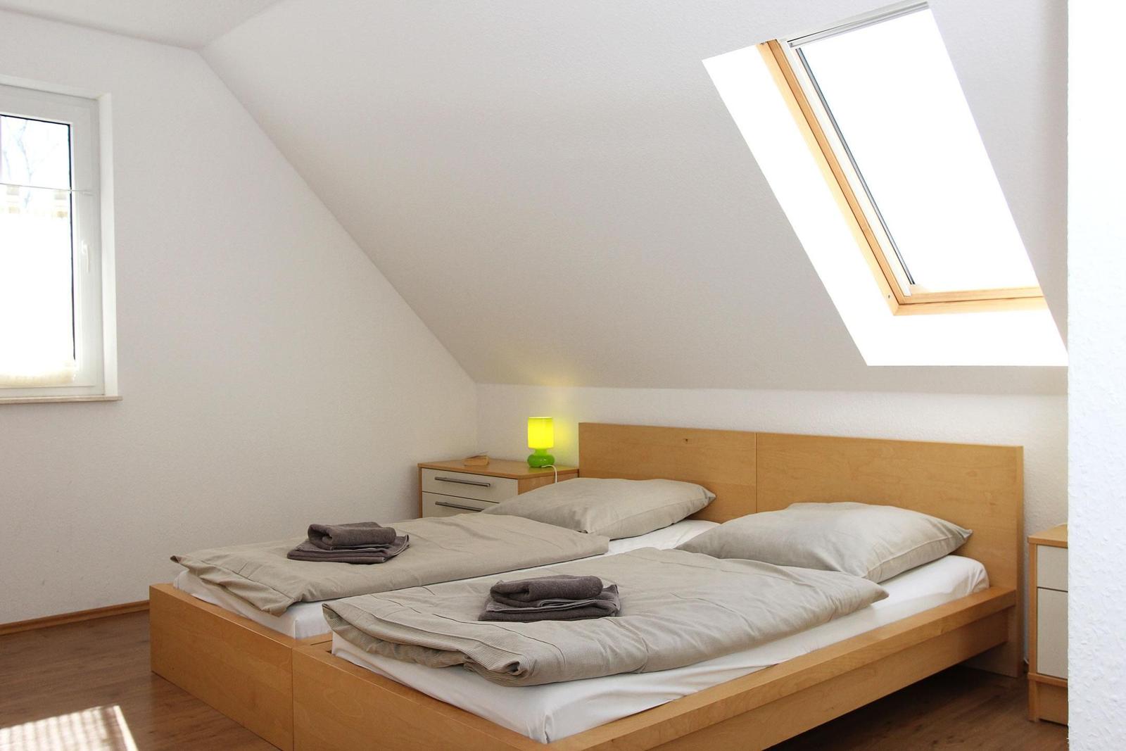Schlafzimmer mit Doppelbett, Dachfenster und Nachttisch.