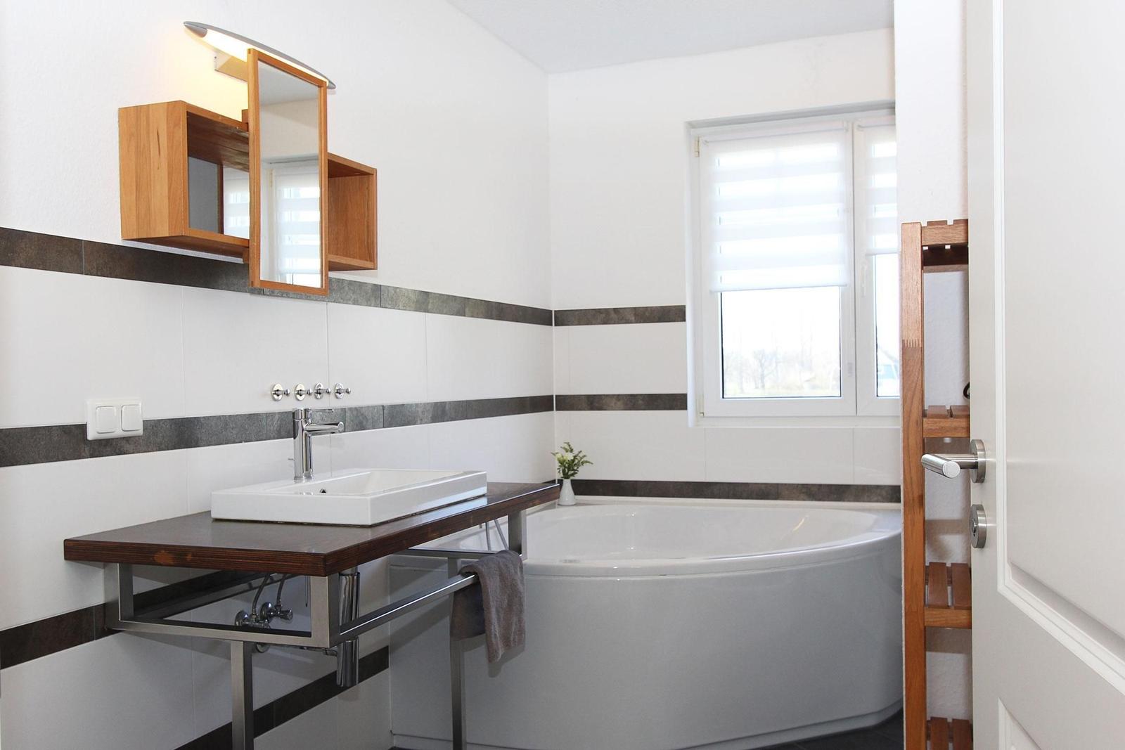 Badezimmer mit Badewanne, Waschbecken und Holzregal