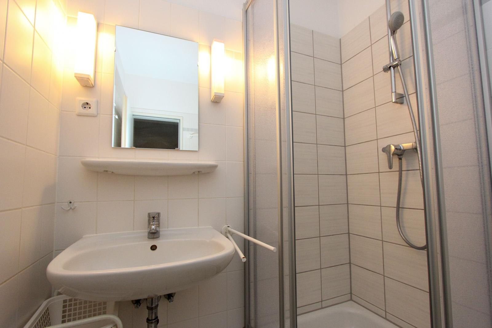 Badezimmer mit Dusche, Waschbecken und Spiegel