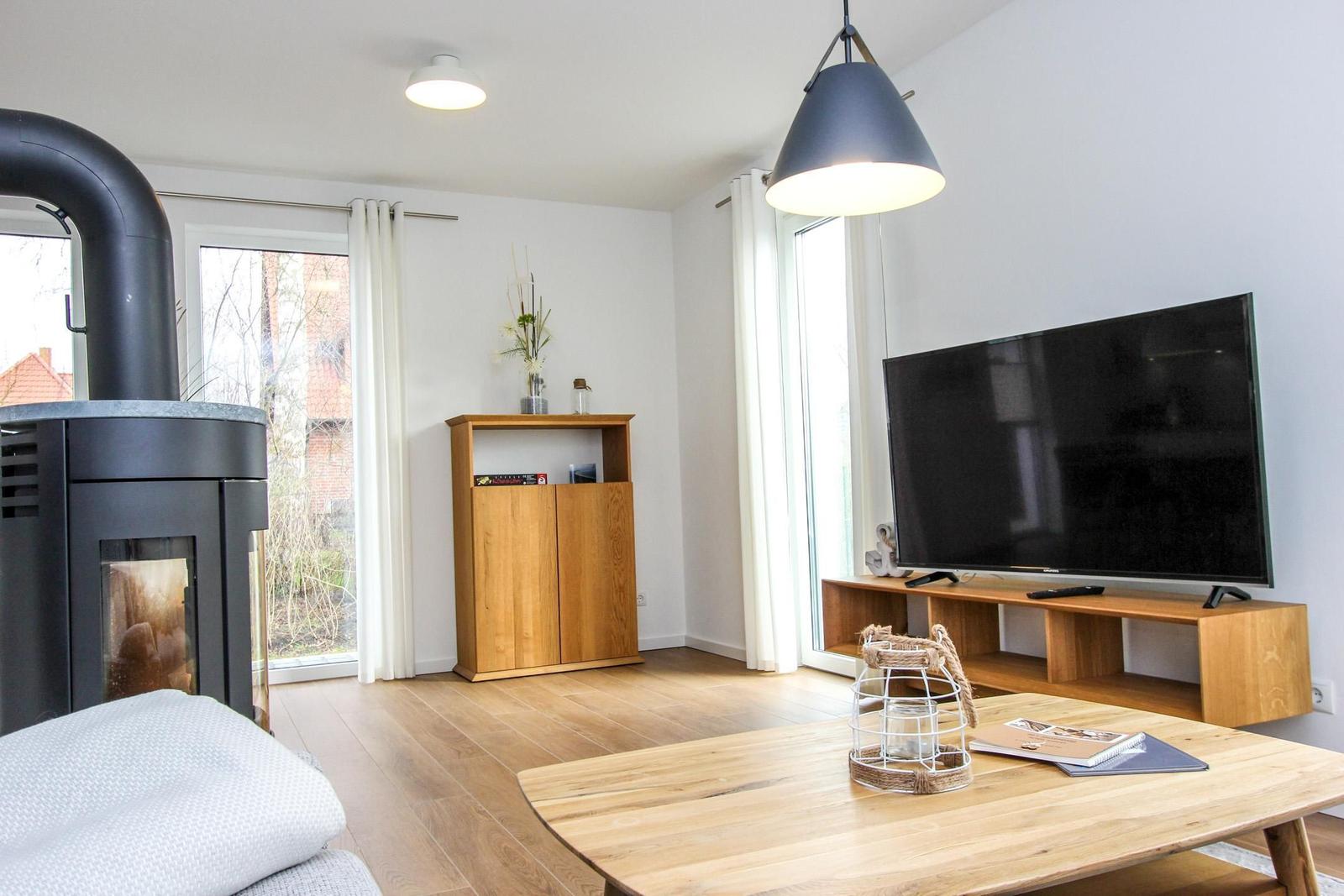 Wohnzimmer mit Holzboden, Fernseher, Kamin und Holzmöbel.