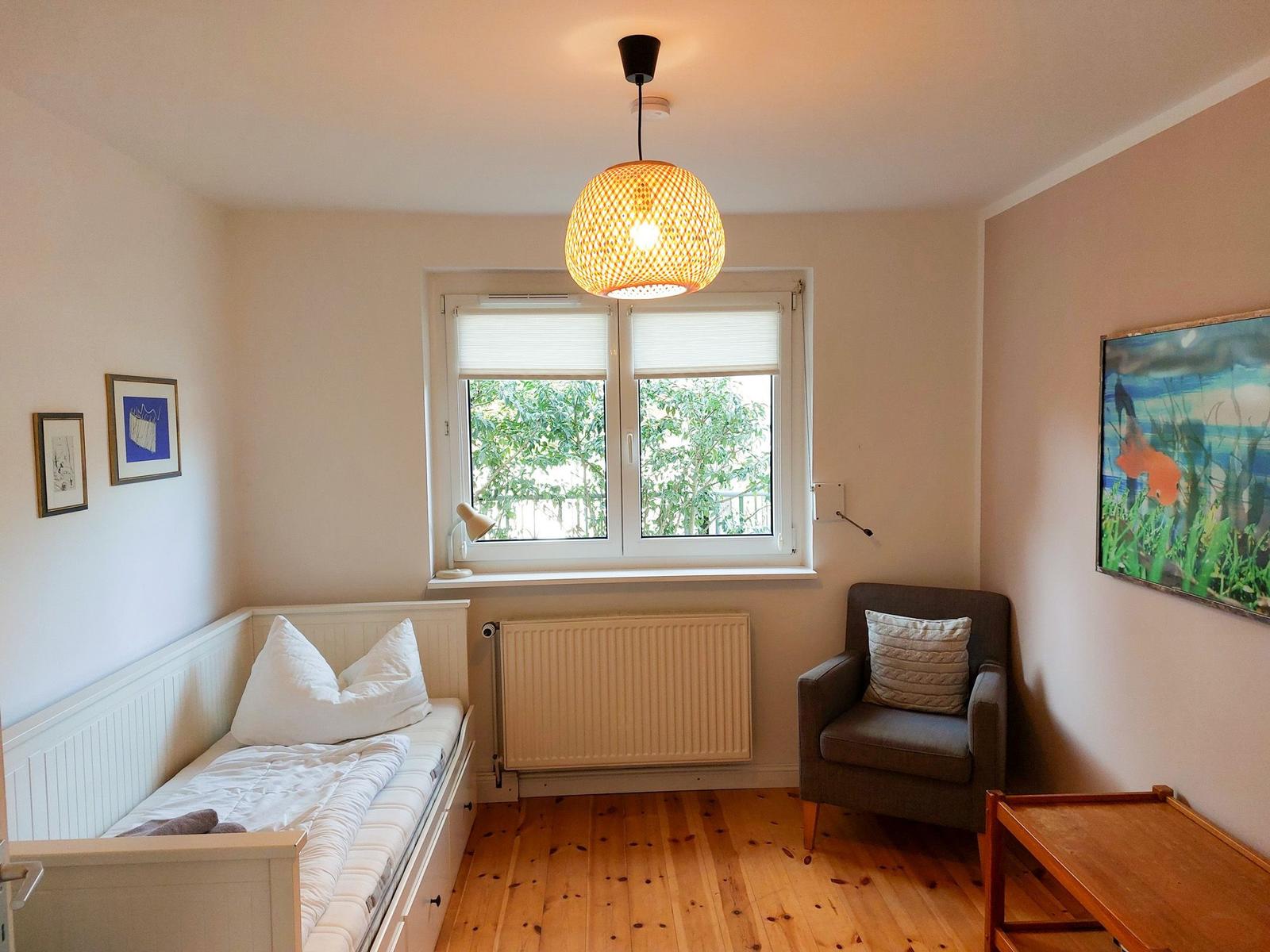Zimmer mit Bett, Sessel, Fenster und Deckenleuchte.