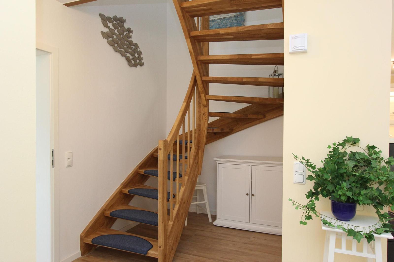Holztreppe mit blauen Stufen, weiße Schrankwand und Pflanze auf Ständer