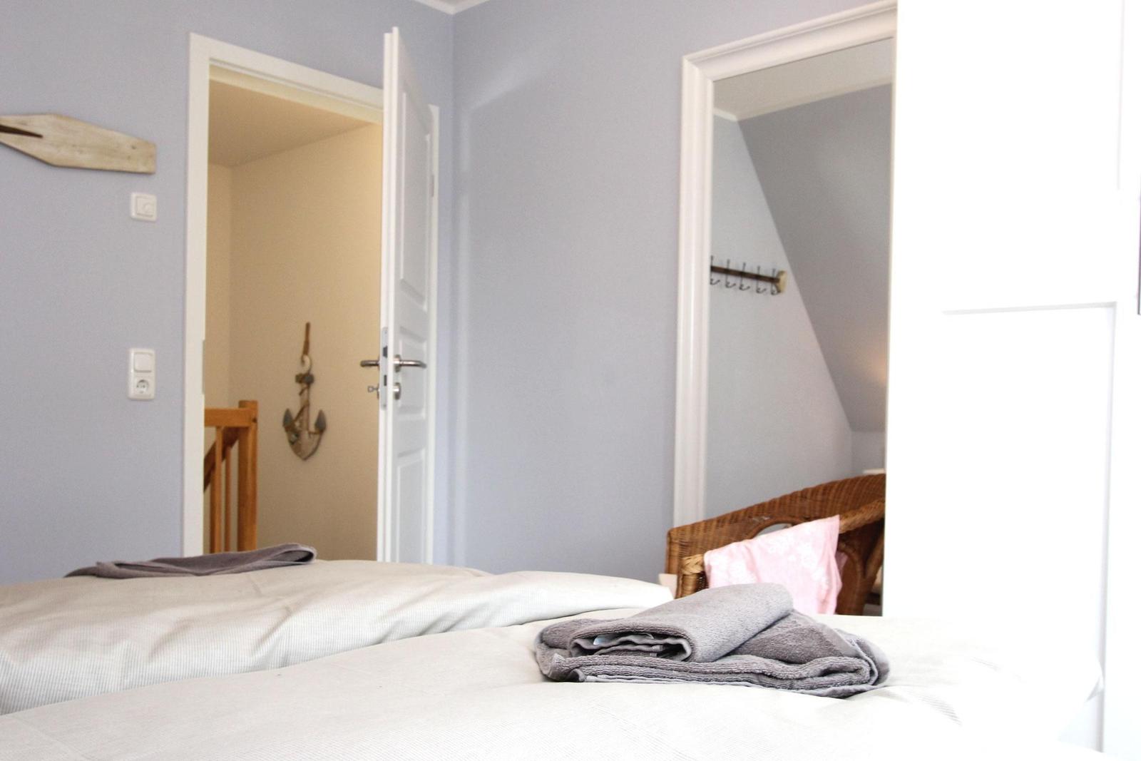 Schlafzimmer mit Bett, Handtuch und Blick in angrenzende Räume.