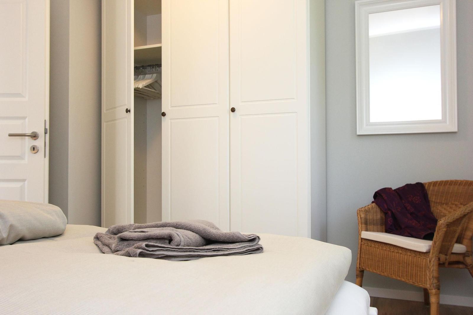 Schlafzimmer mit Bett, Kleiderschrank und Wickerstuhl.