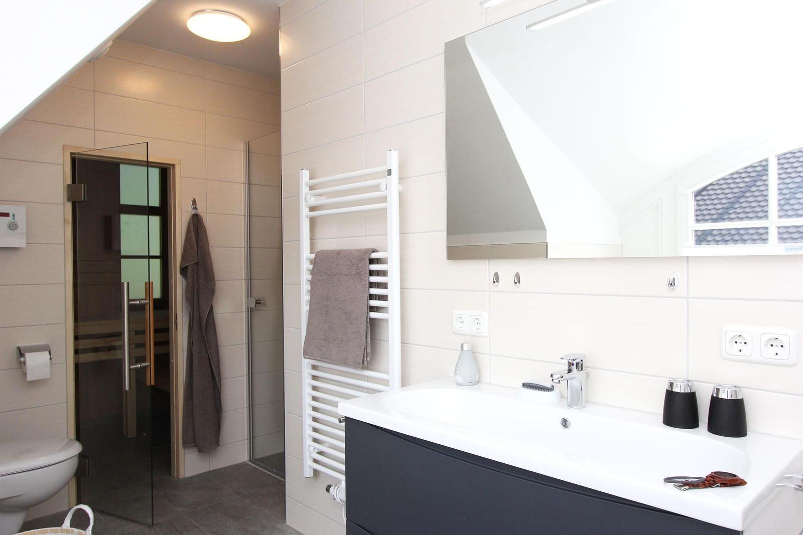 Badezimmer mit Dusche, Toilette und Waschbecken mit Spiegel.