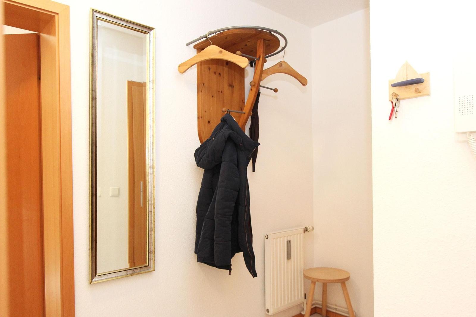 Eingangsbereich mit Spiegel, Kleiderständer und Stuhl.