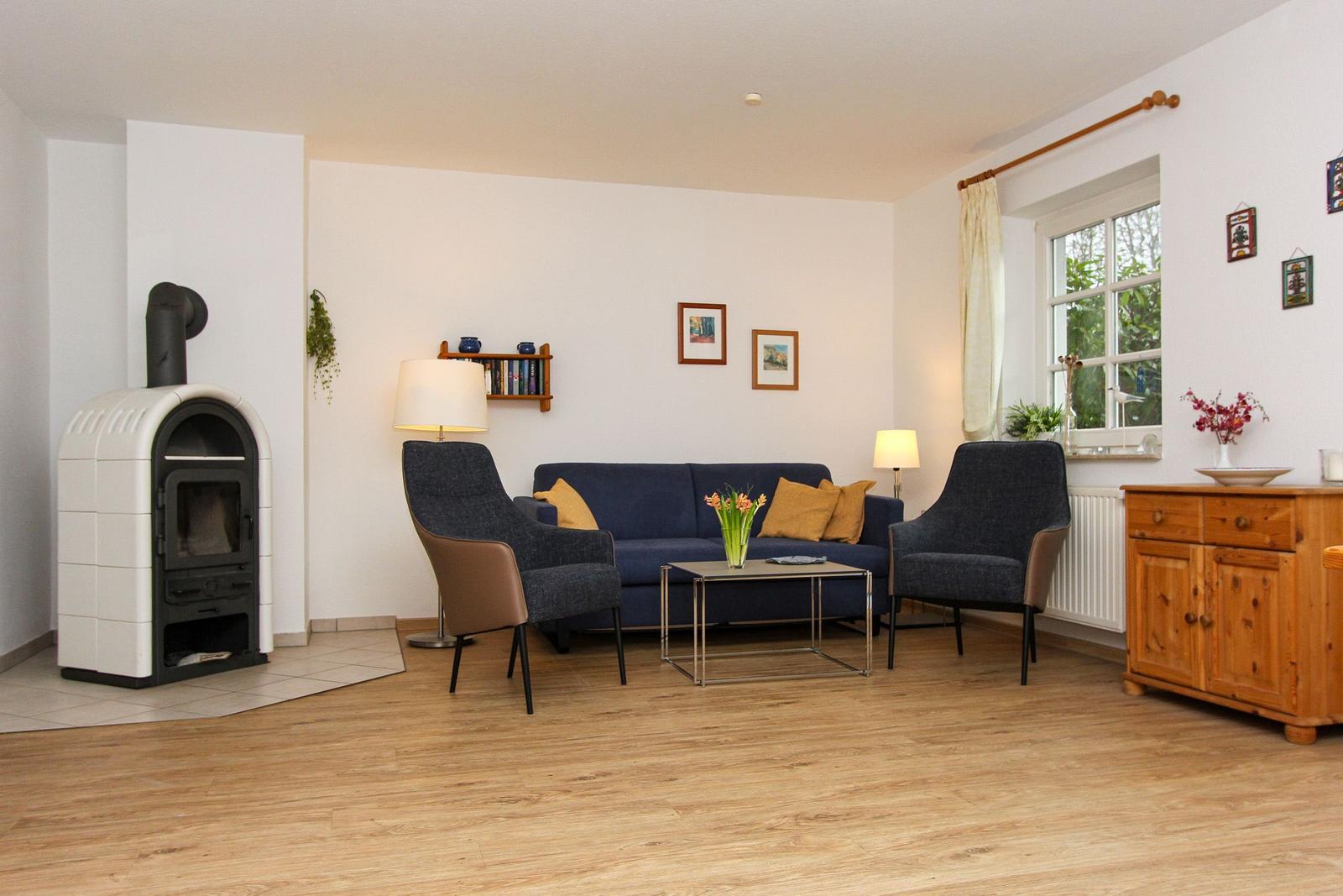 Wohnzimmer mit Sofa, zwei Sesseln, Kamin und Holzboden.