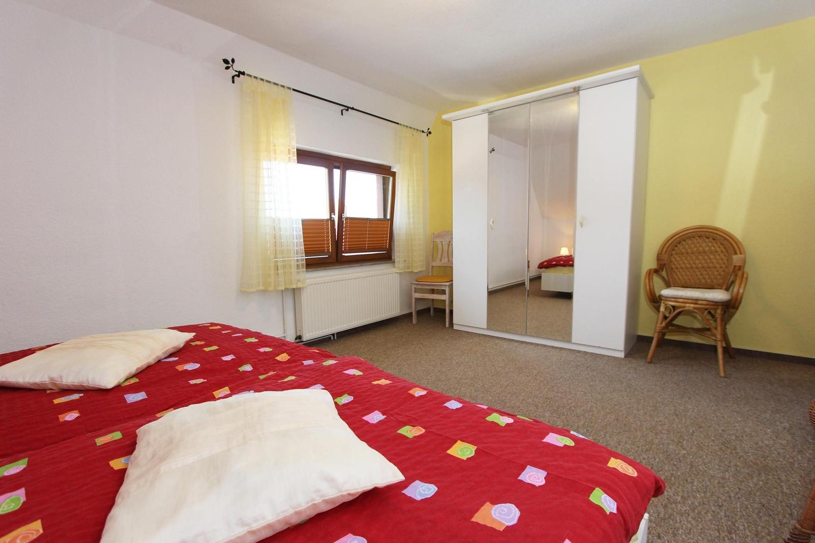 Schlafzimmer mit Bett, Kleiderschrank und Stuhl