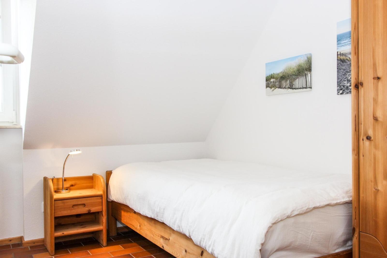 Schlafzimmer mit Holzbett, Nachttisch und Wandbildern
