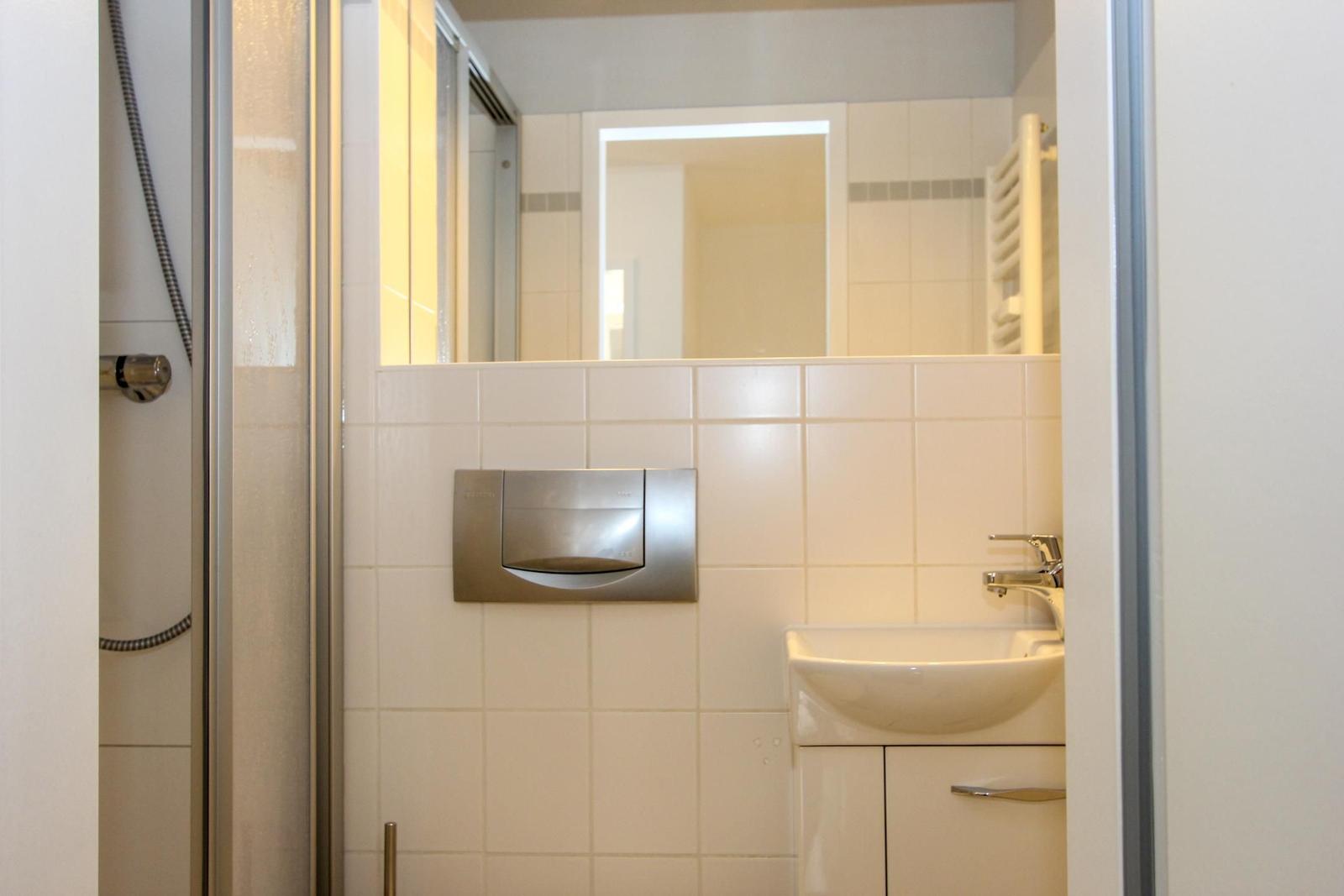 Badezimmer mit Dusche, Waschbecken und Spiegel