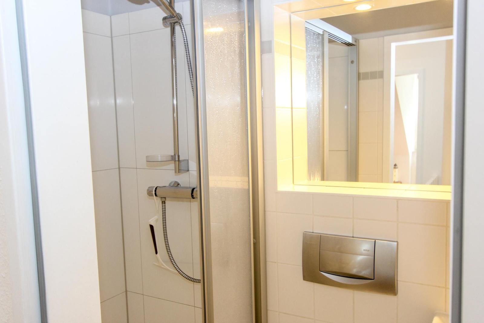 Dusche mit Duschbrause und Spiegel mit Beleuchtung