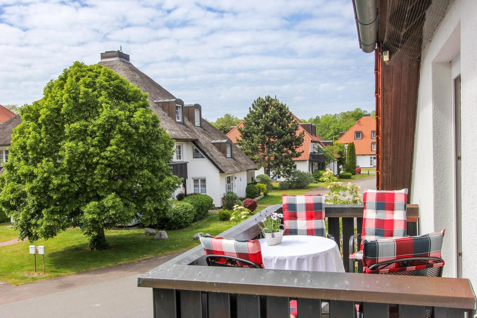Terrasse mit Tisch und Stühlen, Blick auf traditionelle Häuser mit Schindeldächern und grüne Bäume.