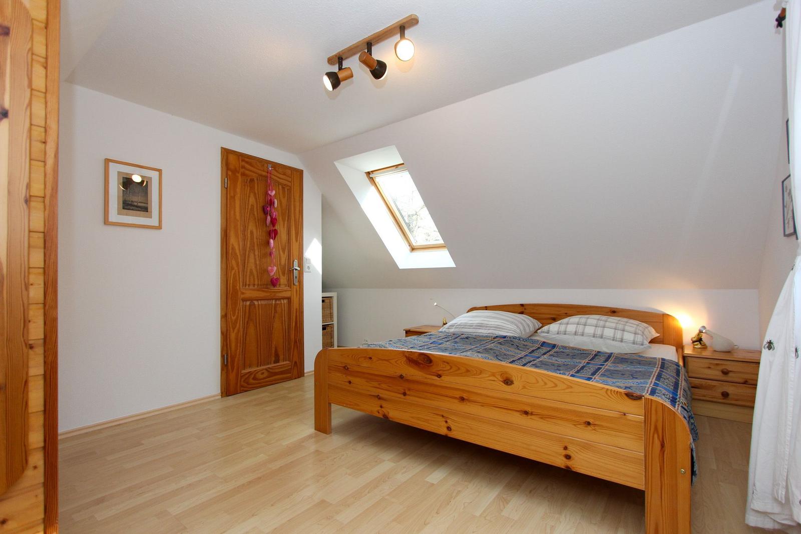 Schlafzimmer mit Holzbett, Dachschiebefenster und Nachttisch