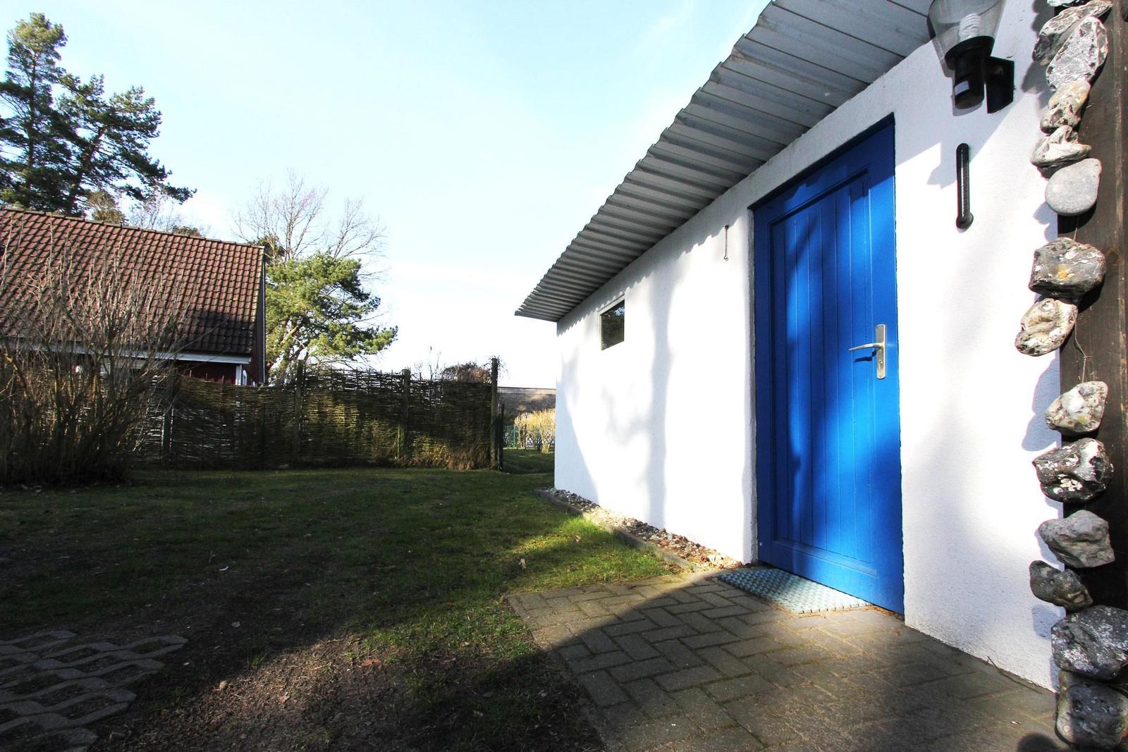 Wohnung mit blauer Tür, weißer Wand und Steinverkleidung an der Seite.