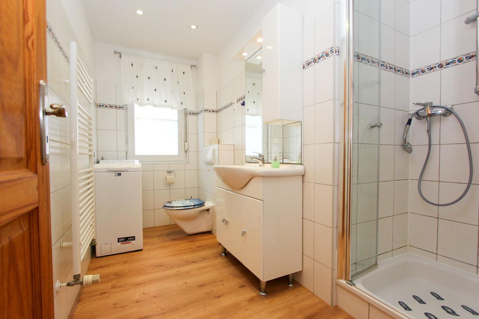 Badezimmer mit Dusche, Waschbecken, WC und Waschmaschine.