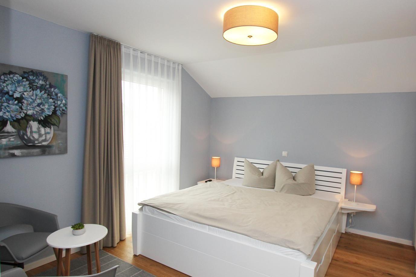 Schlafzimmer mit Bett, Nachttischen, Lampe und Wandbild.