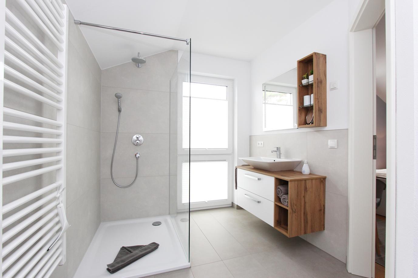 Moderne Badewanne mit Dusche, Waschbecken und Holzregal an der Wand.